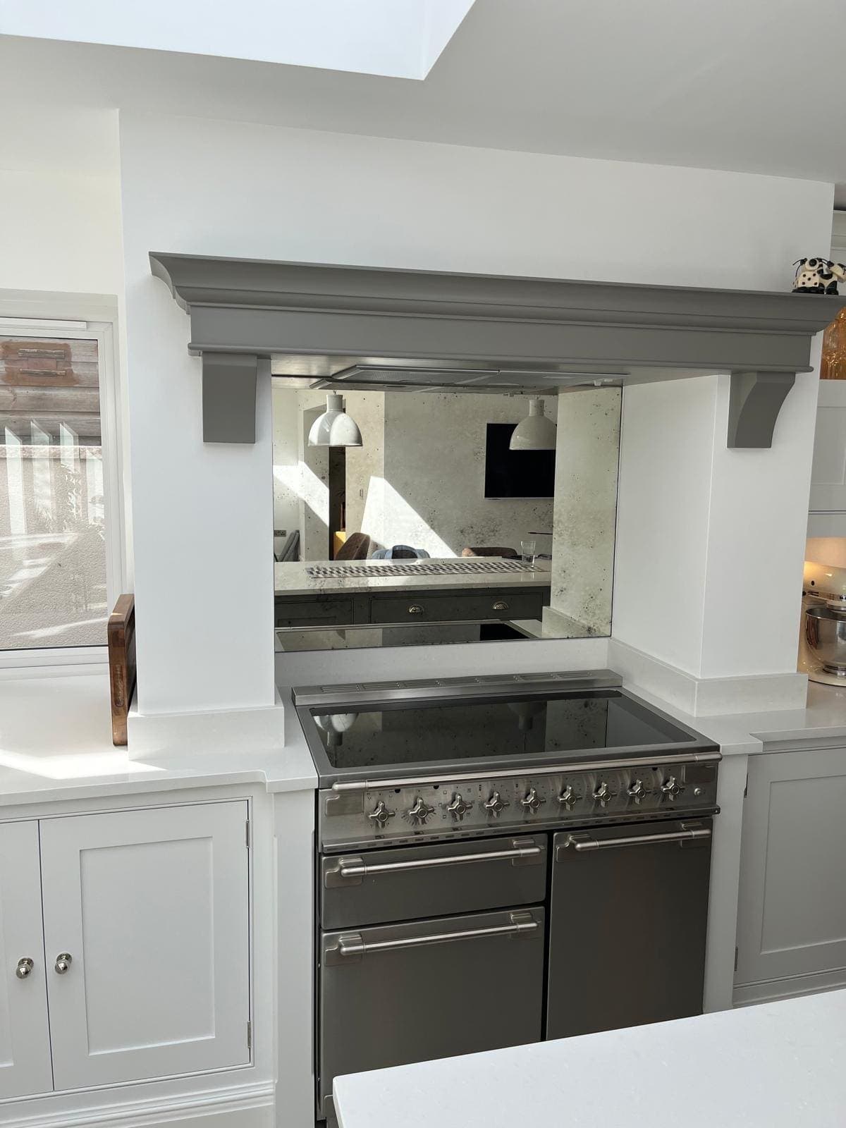 Antique mirror splashback inside a painted chimney surround behind a range cooker