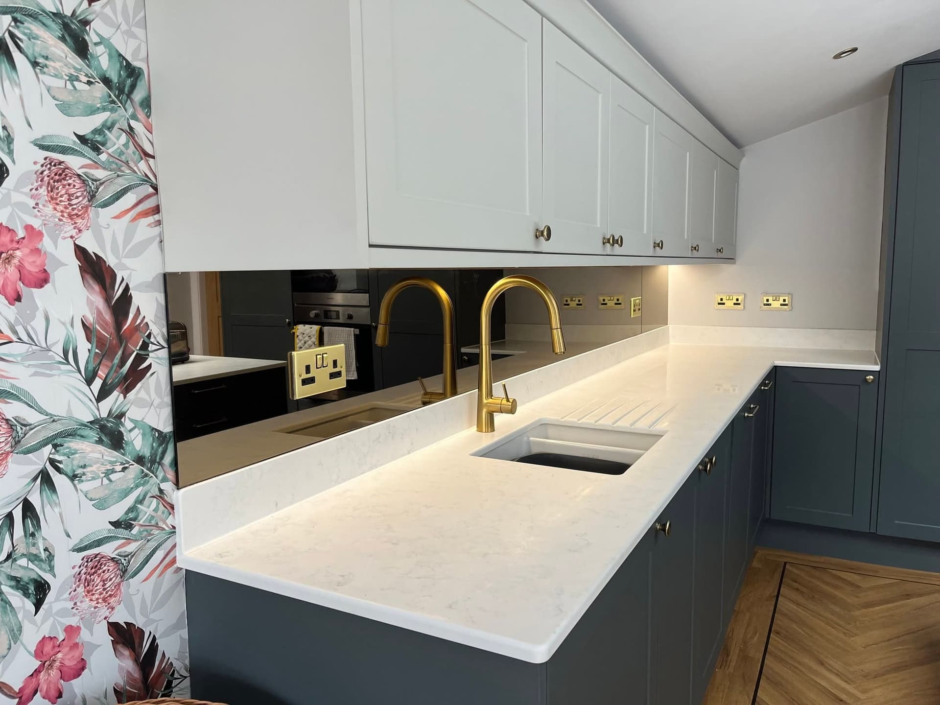 Bronze mirror splashback in a dark grey shaker kitchen with brass taps