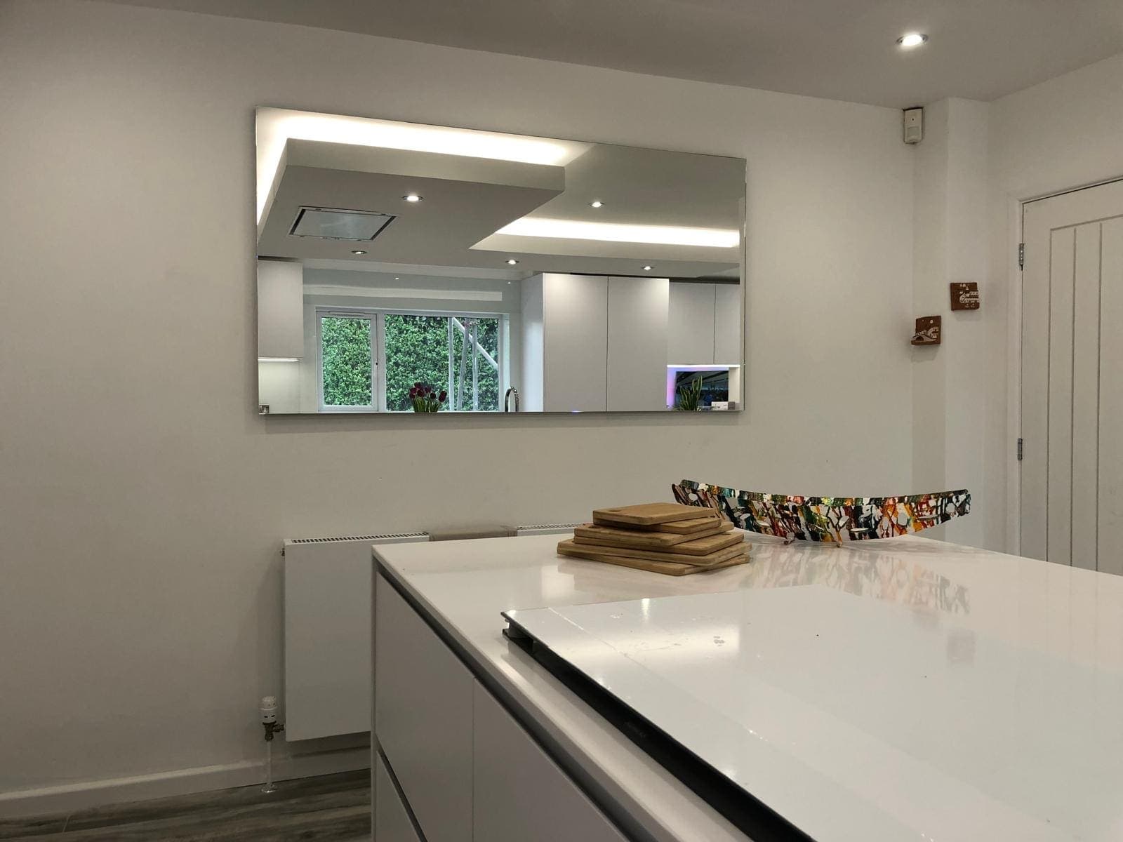 Frameless rectangular wall mirror in a white kitchen-diner
