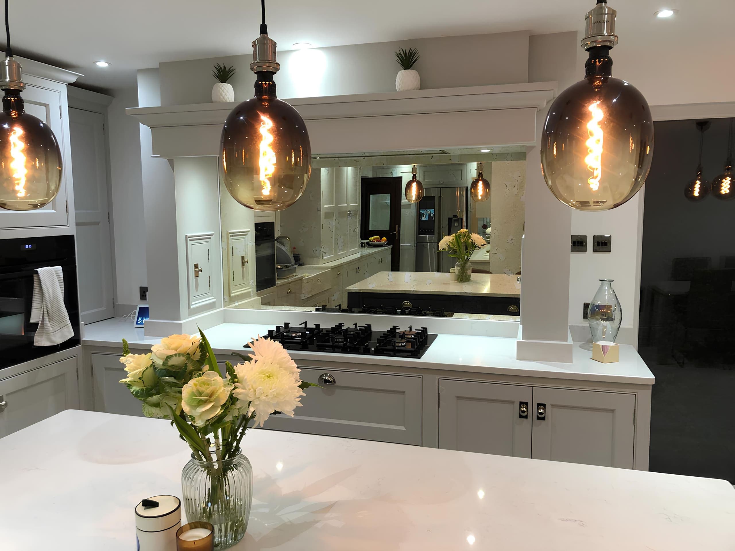 Modern kitchen with a bespoke glass splashback in a mirrored finish, fitted behind the hob and worktop area.
