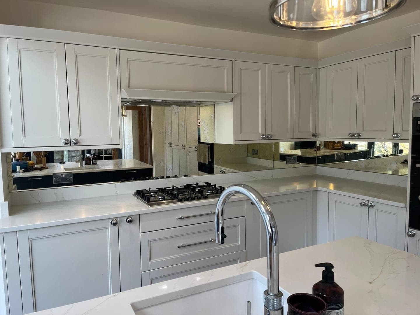 Mirrored glass splashback running around a white shaker kitchen