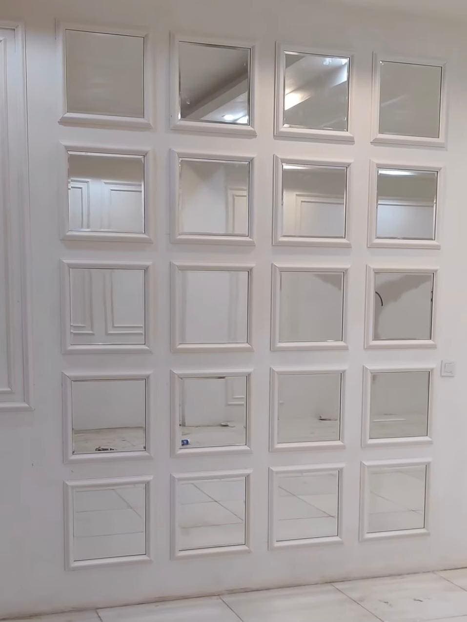 White wall panelling inset with a grid of small mirror panels